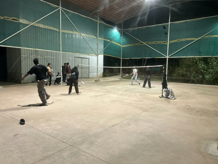 Friends playing badminton on a floodlit court at night